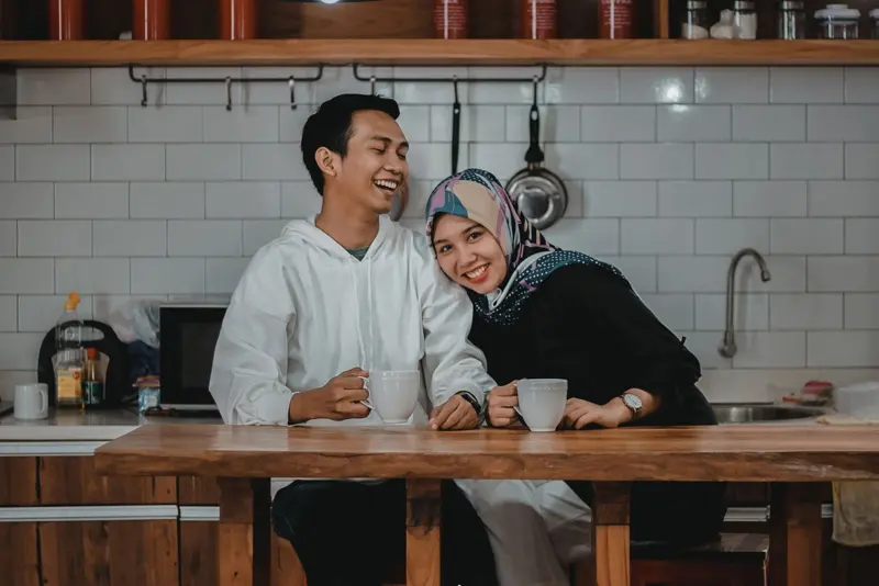 A laughing couple having coffee at the kitchen table
